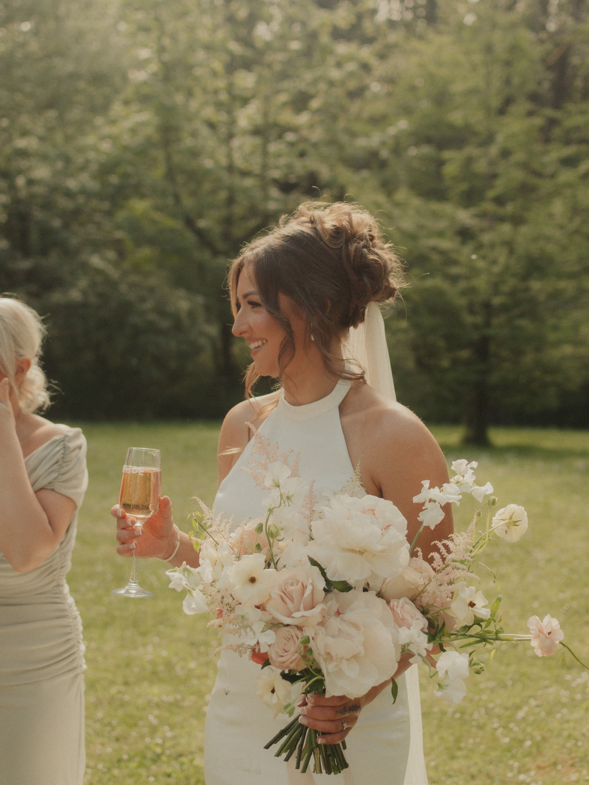 Bride with bouquet and champagne at an outdoor Cornwall wedding